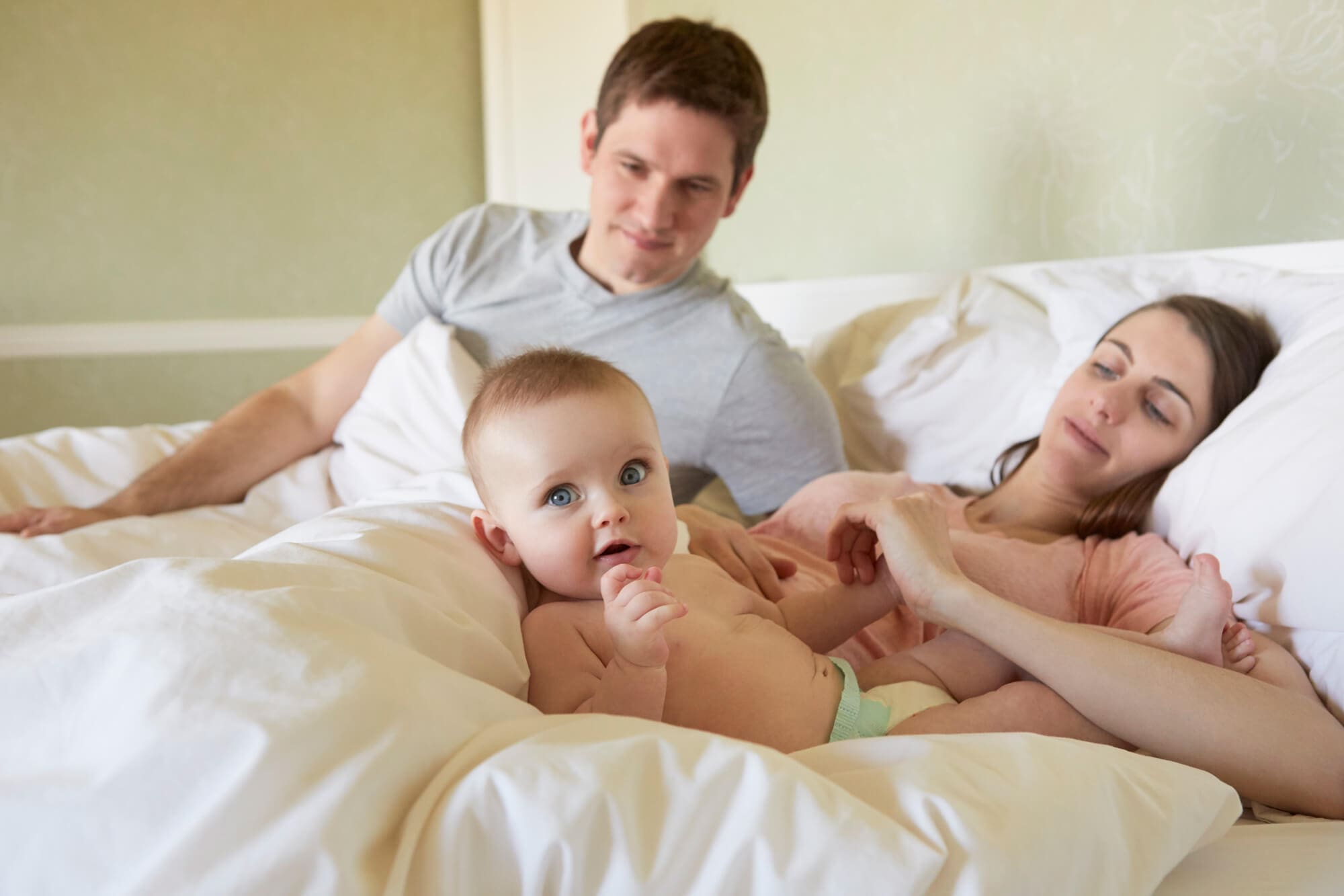 De nouveaux parents avec leur bébé sur leurs nouveau matelas